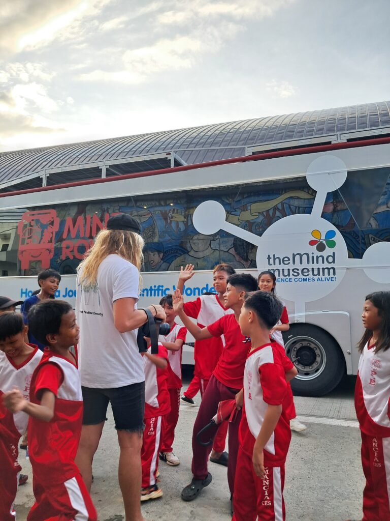 Students and a volunteer beside the Mind Museum Bus in Siargao