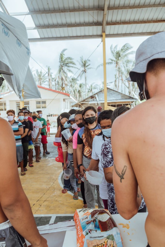 Community members queue with containers during the Odette relief distribution