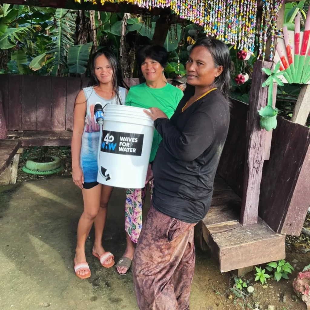 Three community members with a Waves for Water filter bucket