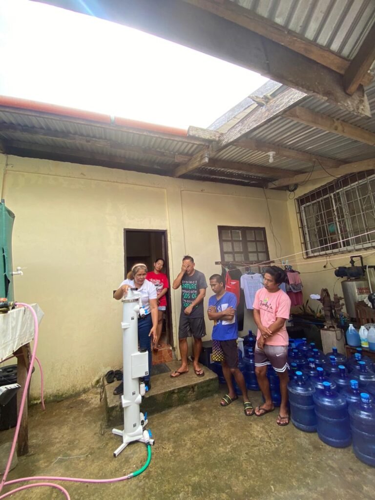 Community members beside the Burgos SkyHydrant installation and water containers
