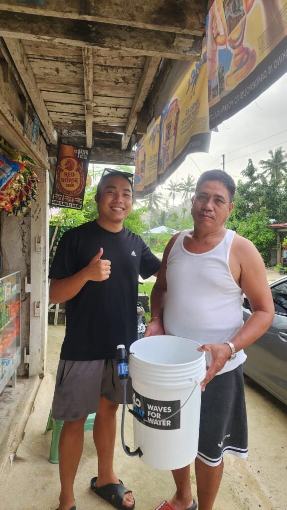 Volunteer and community member with a Waves for Water bucket